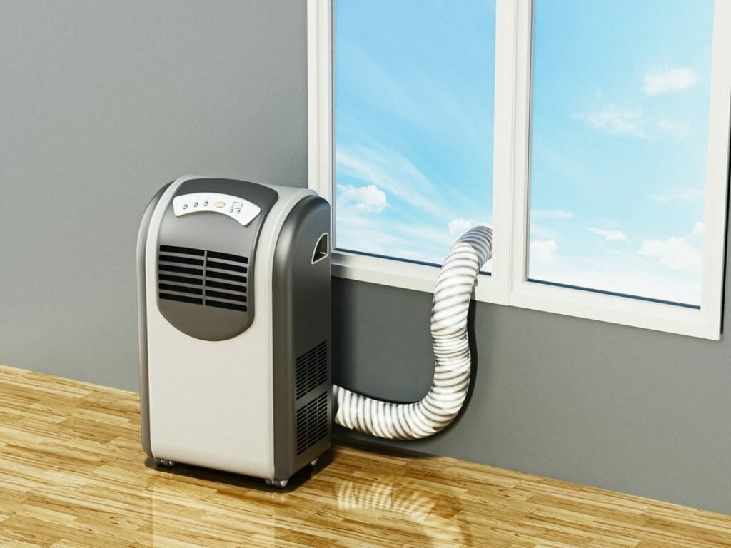 Mobile Klimaanlage steht in Raum und leitet Abluft über einen Schlauch durch ein Fenster